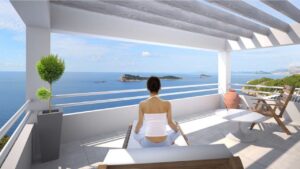 Dame som sitter på terrassen og ser utover havet.